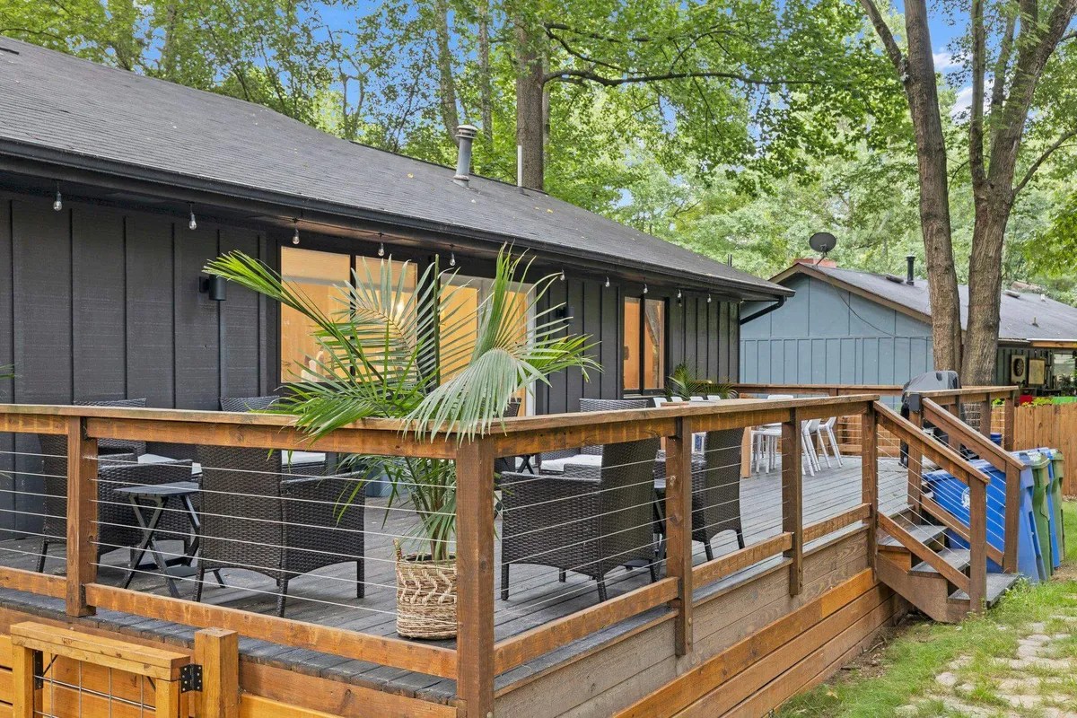 A wooden deck features a potted palm plant and a cozy seating area, all overlooking a peaceful, green landscape. The setting is ideal for relaxing outdoors, sipping morning coffee, or enjoying a sunset view.