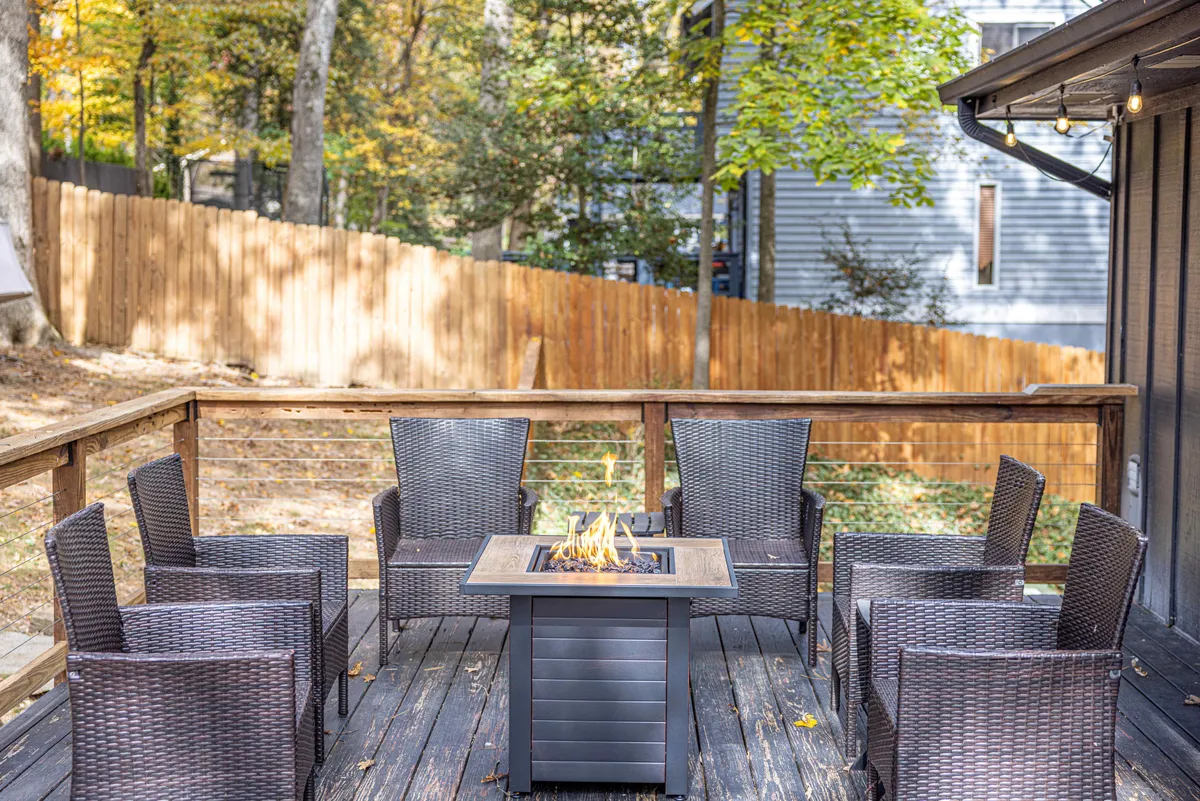 A rustic wooden deck with a fire pit surrounded by comfortable seating offers a warm, communal outdoor space. The natural backdrop enhances the inviting, social atmosphere for gatherings or quiet reflection.